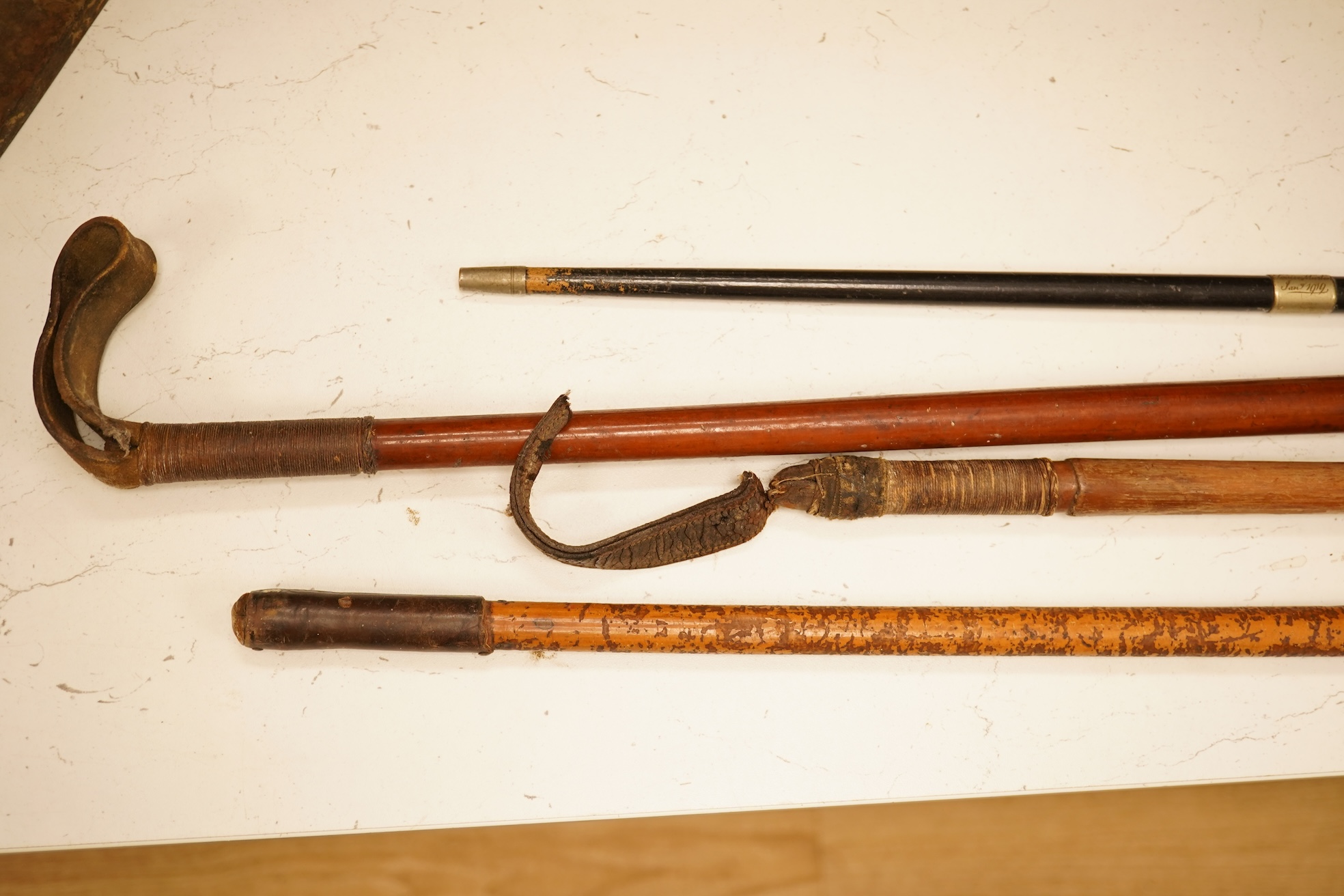 Three early 20th century antler handles riding crops with silver mounts and a swagger stick engraved Louise Martin, 1919